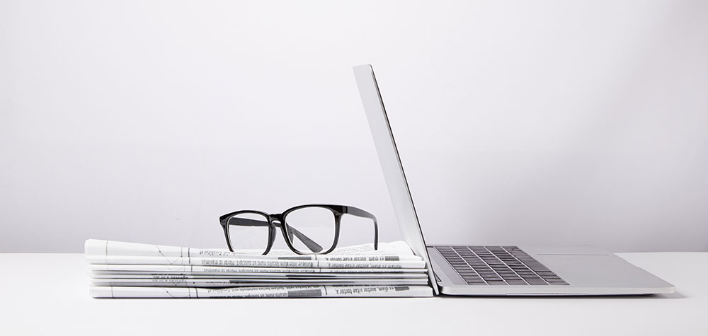 Stack of newspapers beside a laptop